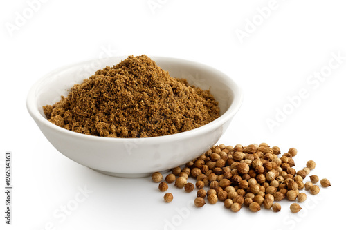 Ground coriander seeds in white ceramic bowl isolated on white. Whole dried coriander seeds.