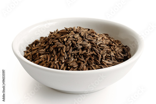 Caraway or cumin seeds in white ceramic bowl isolated on white.