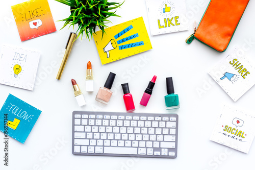 Female blogger concept. Work desk with keyboard, cosmetics and social media icons on white desk top view