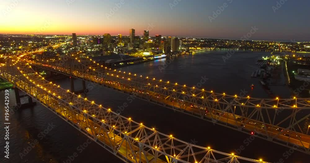 Beautiful night stationary aerial shot of the Crescent City Bridge over the Mississippi River revealing the New Orleans Louisiana skyline.