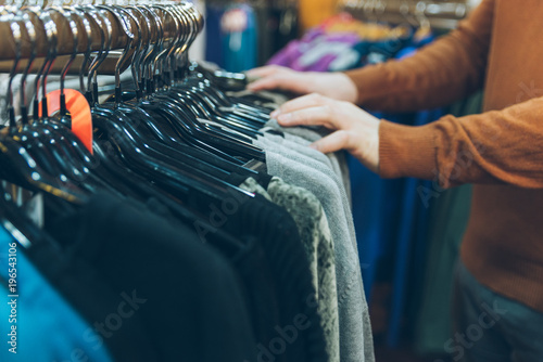 man hands close up looking for clothes in store. shopping concept