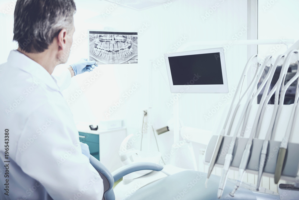Portrait of a senior dentist analising x-ray in dental clinic