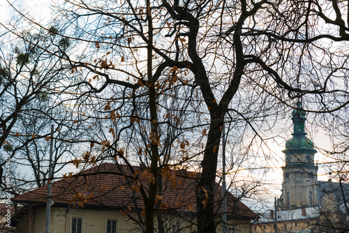 old church tower in front of tree without leaves. autumn season.