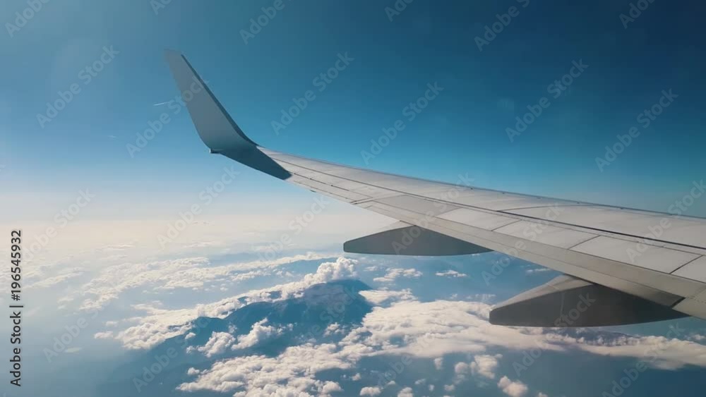 Plane wing view of a plane flying over the clouds
