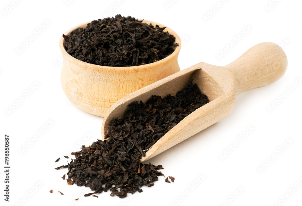Black tea leaves in wooden plate and spoon on a white Black tea leaves in wooden plate and spoon on a white
