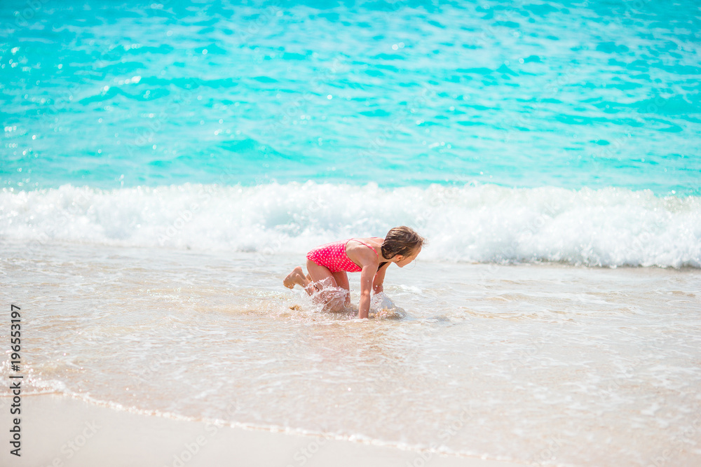 Adorable little girl at beach having a lot of fun in shallow water ...