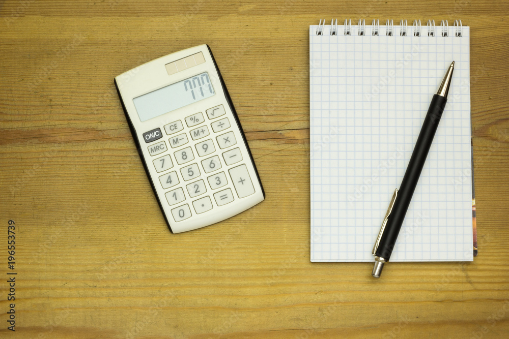 Wooden table at office with calculator, pen and paper. Background with copy space. Wooden table at office with calculator, pen and paper. Background with copy space.