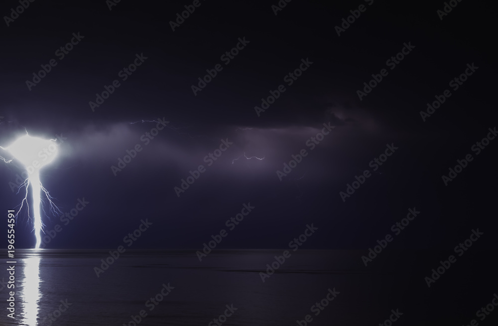 lightning bolts reflection over the sea. taken during a thunderstorm over the ocean with clouds in the background lightning bolts reflection over the sea. taken during a thunderstorm over the ocean with clouds in the background