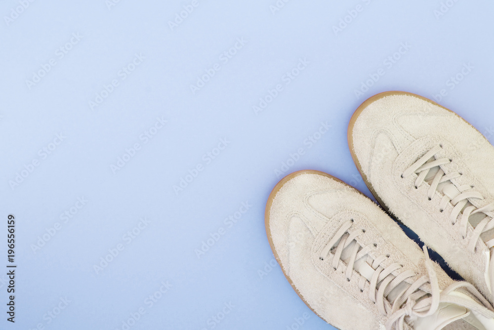 Light sneakers on a bright blue background. Minimalistic composition with sneakers and spotted text. Flat lay