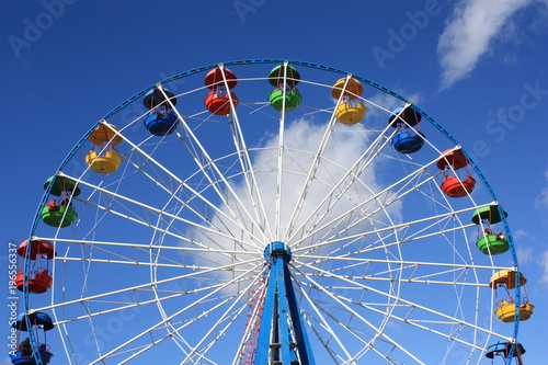 Colourful Ferris Wheel over the blue clear sky with red  green  blue and yellow cabins