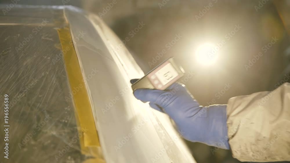 View of measuring a thickness of primer on a car surface using a thickness gauge