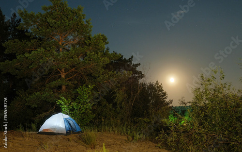 tourist tents on a sandy beach at night with moonlight surrounded by trees under a starry sky advertising background