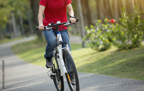 one woman cyclist riding bike in tropical spring park