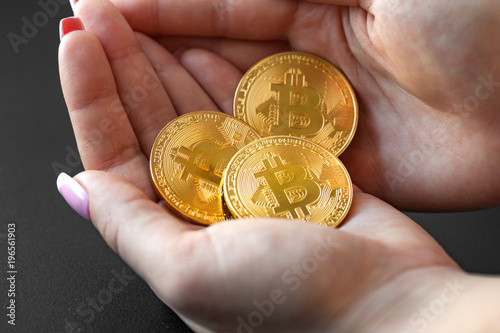 The female hands hold the three coin on the dark background