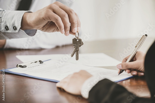 Young woman is signing financial contract with male realtor photo