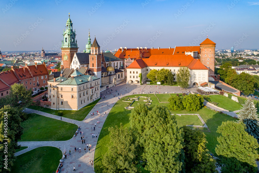 Royal Wawel Gothic Cathedral in Cracow, Poland, with Renaissance Sigmund Chapel with golden dome, part of Wawel Castle, yard, park and tourists. Aerial view in sunset lightl