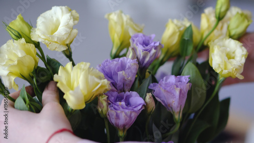 Female hands with beautiful flowers - eustoms of yellow and violet from close range