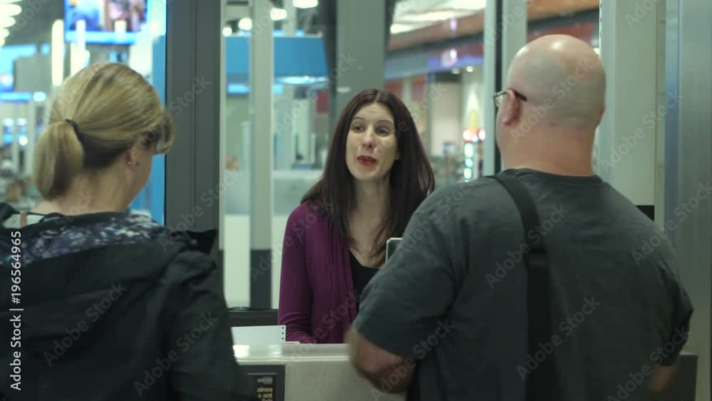Passengers check in with an airline employee for their flight at the airport. Passengers check in with an airline employee for their flight at the airport.