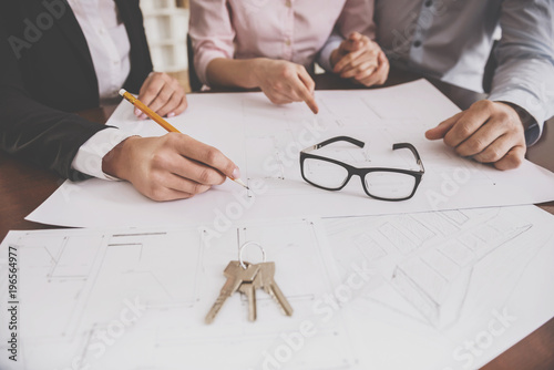 Slika na platnu Female realtor showing contract with floor layout in an apartment to a young cou