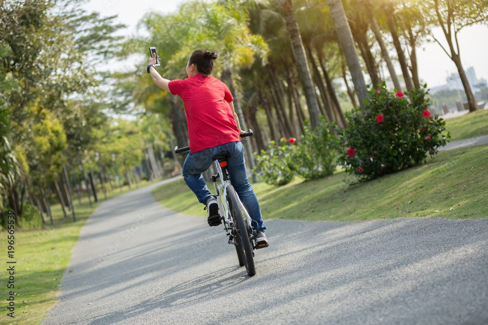 cyclist use cellphone while riding bike in tropical park