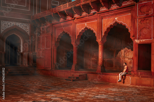 young guy sitting under the rays of the morning sun and watching the Taj Mahal mosque photo