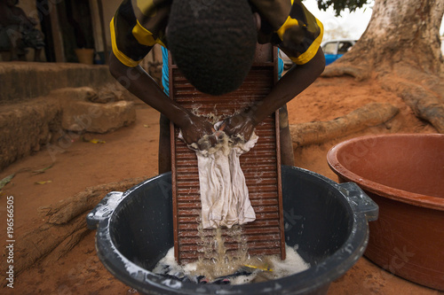 Tableau sur toile Young boy washing dirty clothes in a washing board and tub in the town of Nhacra