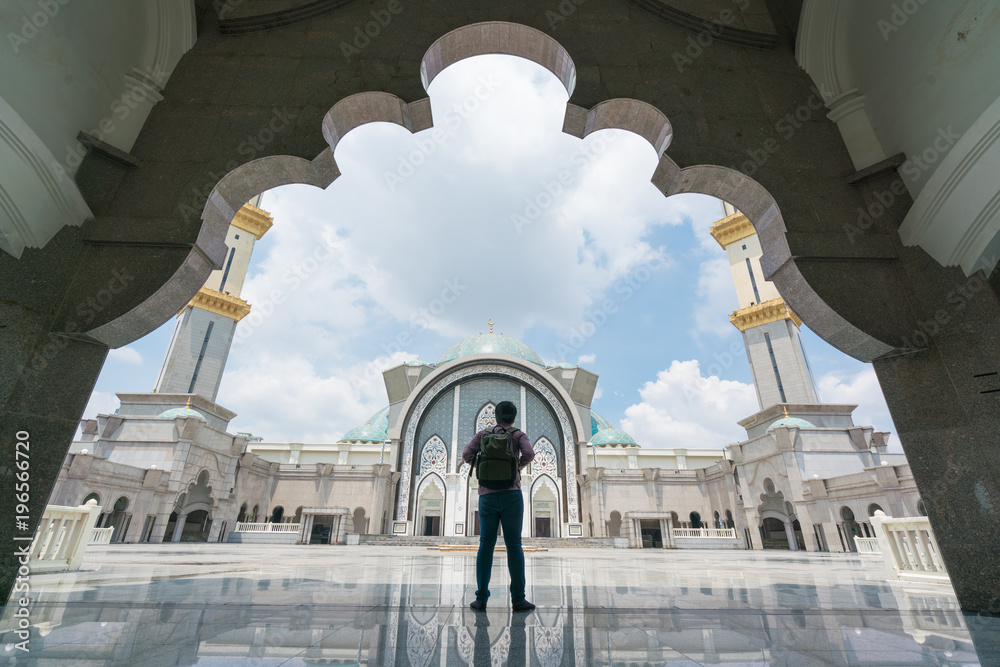Naklejka premium Młody podróżnik z plecakiem idący do meczetu Wilayah Persekutuan w Kuala Lumpur w Malezji.
