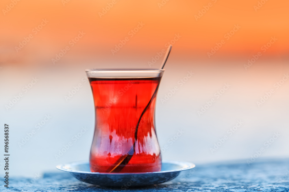 Turkey, Istanbul. Istanbul traveling welcome concept. Traditional Turkish glass of tea on parapet at Maiden tower background. Sunset time scene.