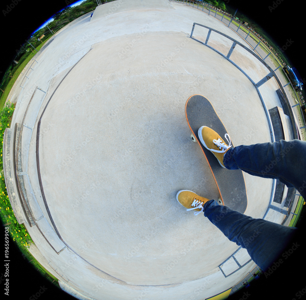 Naklejka premium skateboarder legs riding skateboard at skatepark