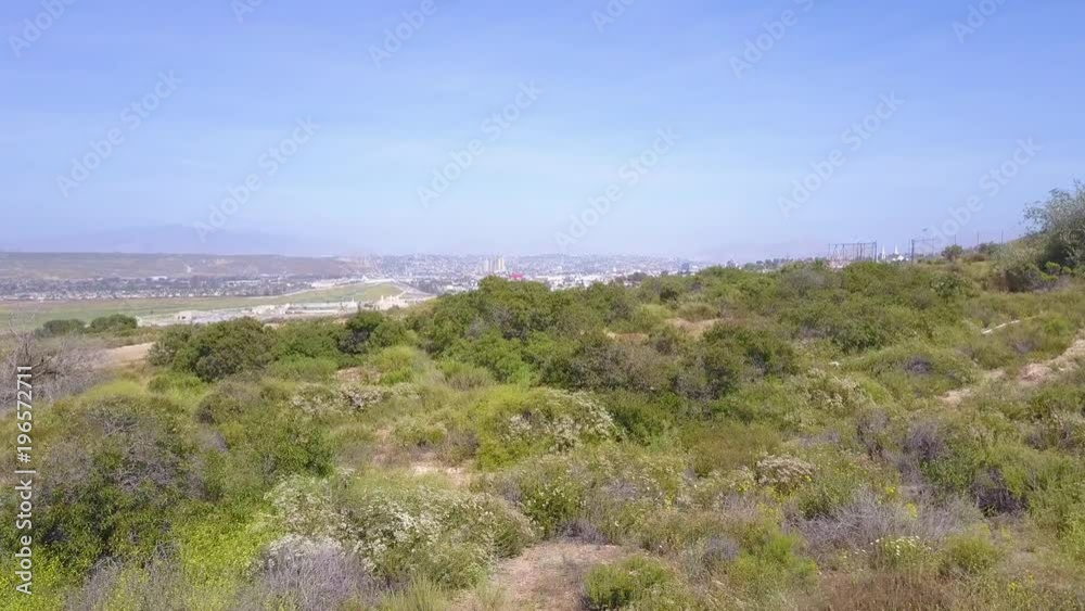 A low aerial over the mountains between Tijuana and San Diego reveals the border wall fence. A low aerial over the mountains between Tijuana and San Diego reveals the border wall fence.