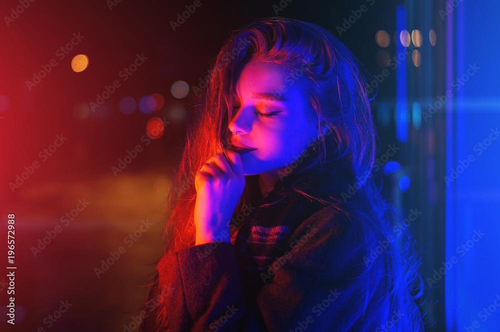 Sexy young woman posing over night city dramatic neon background