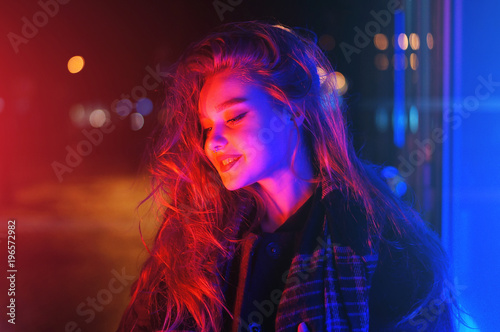 Sexy young woman posing over night city dramatic neon background © morozov_photo