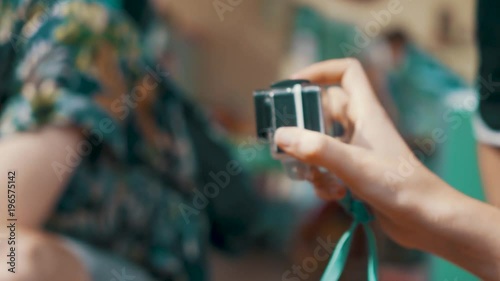 Young female tourist holds a GoPro camera in her hand and films with it