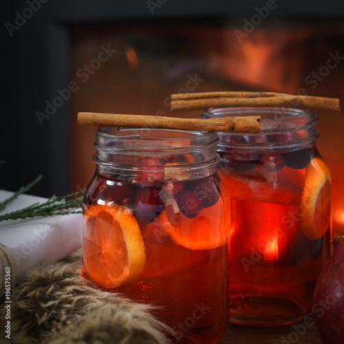 Fototapeta Holiday mulled fruit punch by the fire with cinnamon garnishes