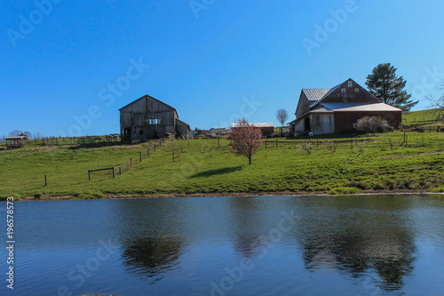 Two barns on a hill overlooking a pond