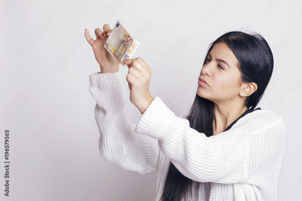 Latin woman checking a fifty euro banknote. Indoors, over a white background. Latin woman checking a fifty euro banknote. Indoors, over a white background.