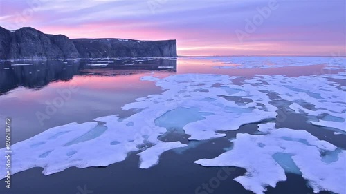 Drifting past sea ice under the midnight sun on Scott Island off Baffin Island in Nunavut, Canada.  photo