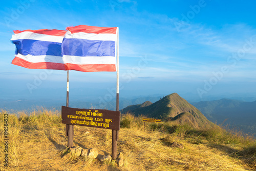 Thailand Flag at mountains on blue sky, Khao Chang Puak at Thong Pha Phum National Park, Kanchanaburi, Thailand. Thai characters mean Khao Chang Puak peak altitude 1249 meter. photo