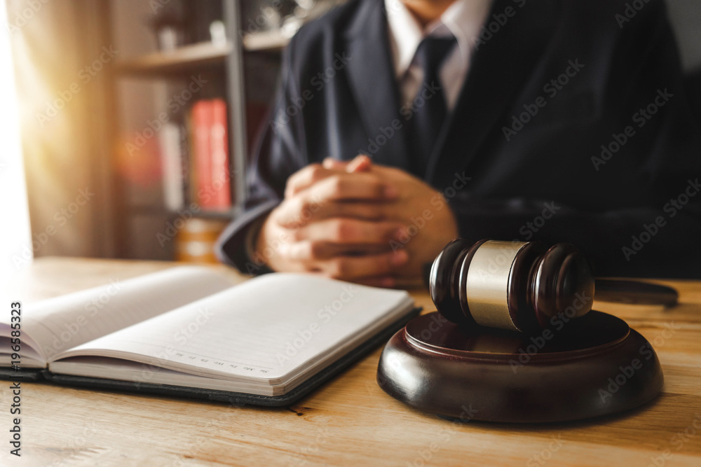 justice and law concept.Male judge in a courtroom  the gavel,working with digital tablet computer on wood table in morning light 
