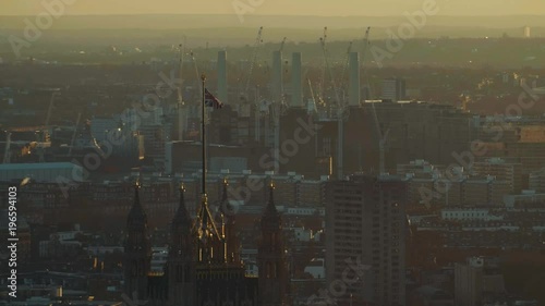 Beautiful slow motion view a the British flag waving in the wind above the Palace of Westminster against a golden sunset