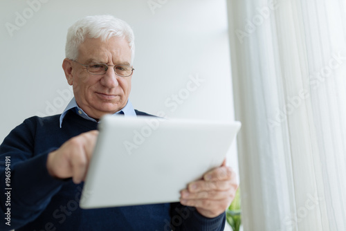 Aged man with digital tablet © DragonImages