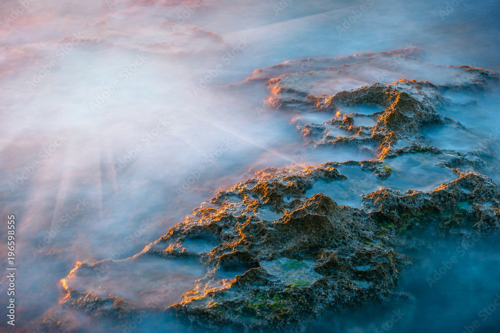 long exposure of sea and rocks at sunset