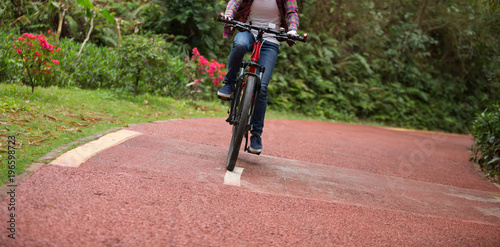 woman cyclist riding bike on forest trail