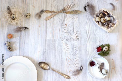 Beautiful table setting for Easter, on the table quail eggs and feathers are combined with plates and cutlery