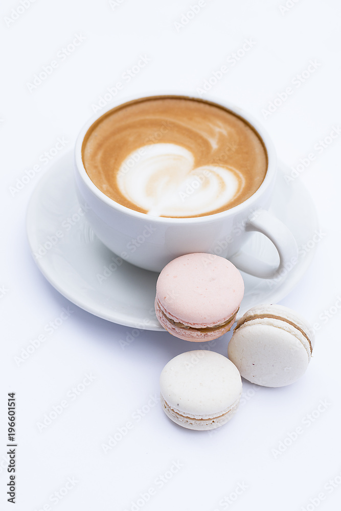 Coffee latte in a white mug and dessert macaroons on a white background. Coffee latte in a white mug and dessert macaroons on a white background.