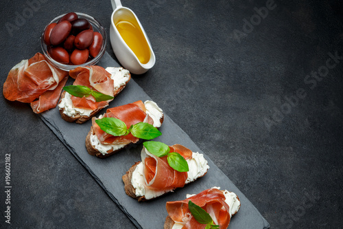 italian food with olives and prosciutto bruschettas on stone board