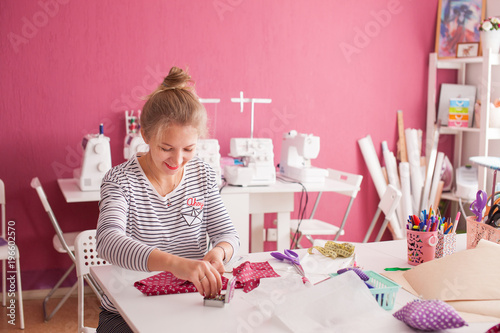 young woman seamstress making pattern on fabric with tailors chalk. Girl working with a sewing pattern. Hobby sewing as a small business concept. Tailor measuring textile material