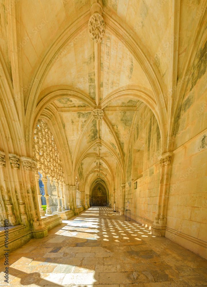 Corridor and manueline colonnade of Royal cloister at Monastery of Batalha or Monastery of Saint Mary of the Victory in Estremadura, Leiria District, Central Portugal. Unesco Heritage. Vertical shot.