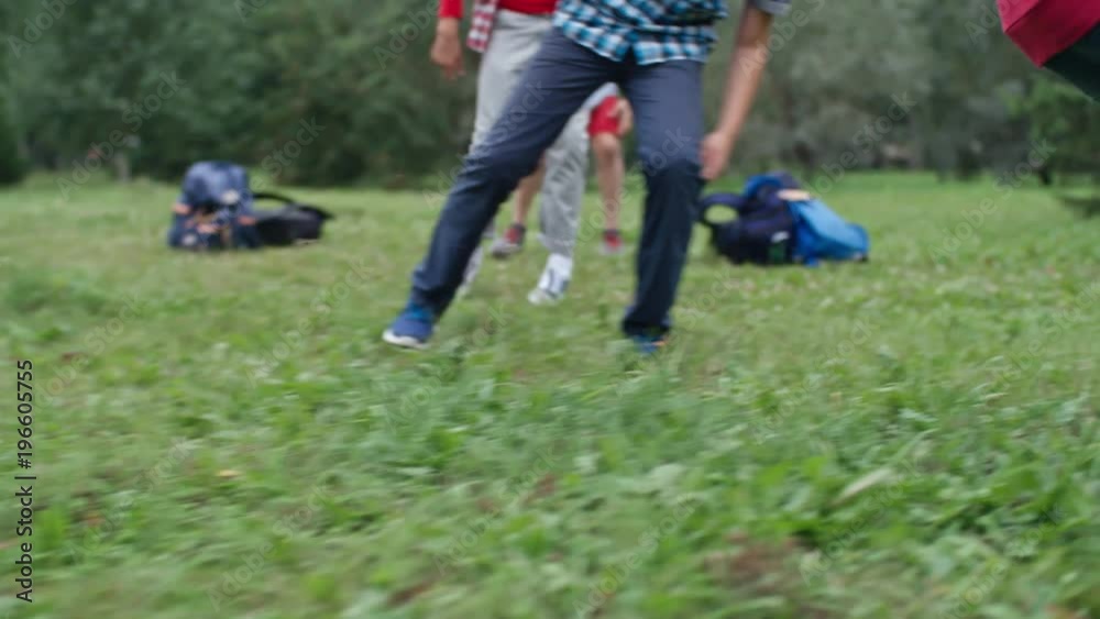 Low angle view of group of classmates playing with football in park during school recess, one dribbling ball and trying to kick it Low angle view of group of classmates playing with football in park during school recess, one dribbling ball and trying to kick it