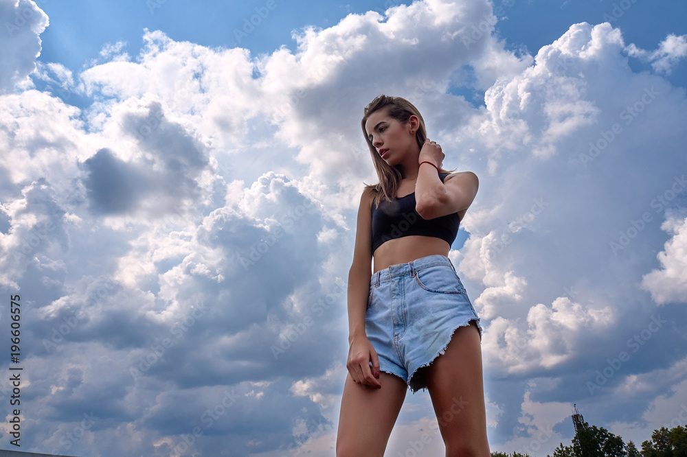Beautiful fashion model on the background of a blue sky with clouds Beautiful fashion model on the background of a blue sky with clouds
